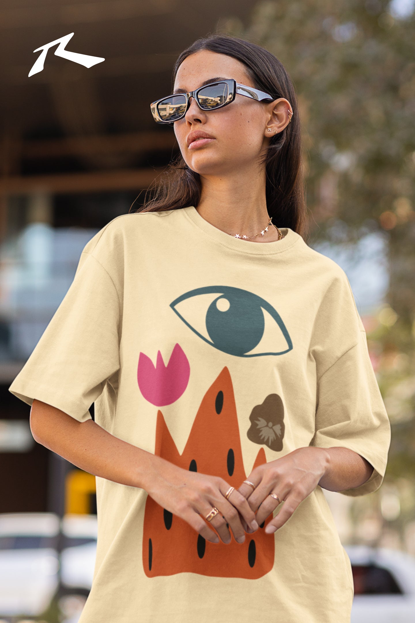 Person wearing a beige t-shirt with a colorful graphic design outdoors.